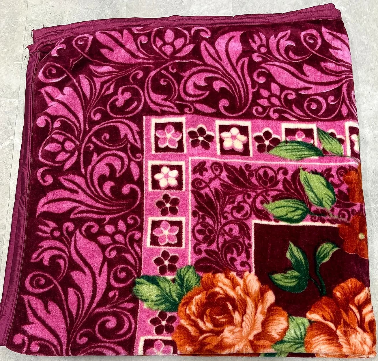Neatly folded square of wine floral mink blanket showing plush thickness