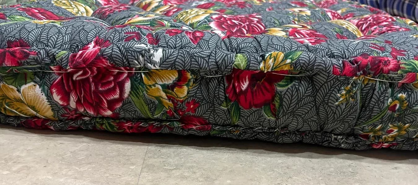 Side profile view of tufted charcoal and rose floral gadda showing layered thickness