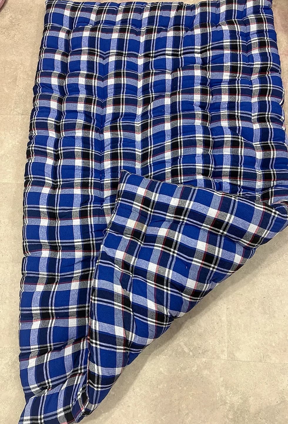 Classic blue plaid tartan quilted mattress or floor gadda folded showing reverse lining
